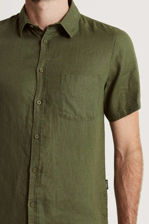 A person wears the Mr Simple Linen Short Sleeve Shirt in olive green, featuring a chest pocket and lightweight fabricβvisible from chest to neck with part of the left arm shownβmaking it perfect for any summer wardrobe.