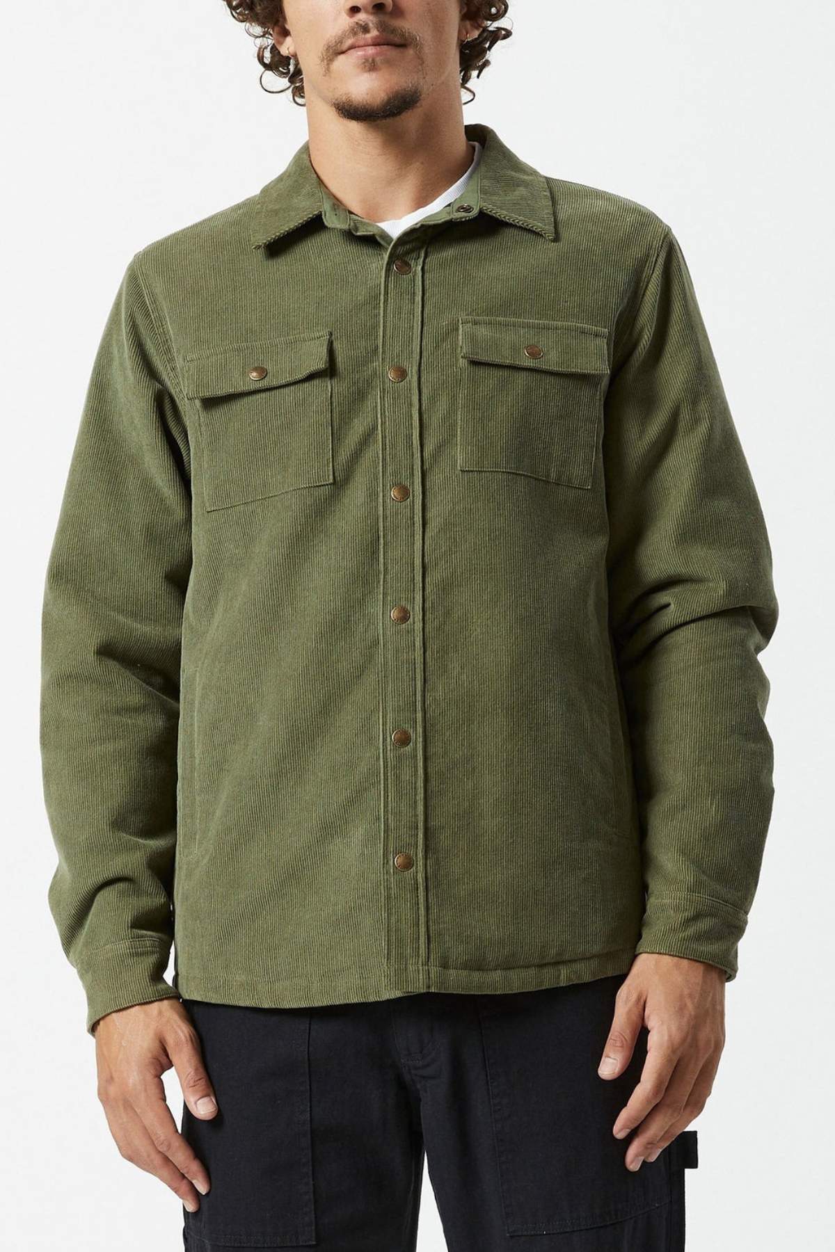 A man in a Mr Simple Quilted Cord Jacket, olive green with two chest pockets and subtle quilted lining, stands against a plain light background.