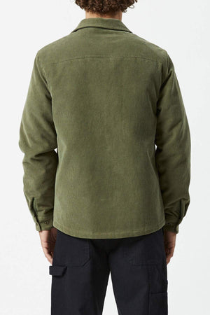 A person with curly hair is seen from the back wearing an olive green, long-sleeve Mr Simple Quilted Cord Jacket and black cargo pants against a plain light background.