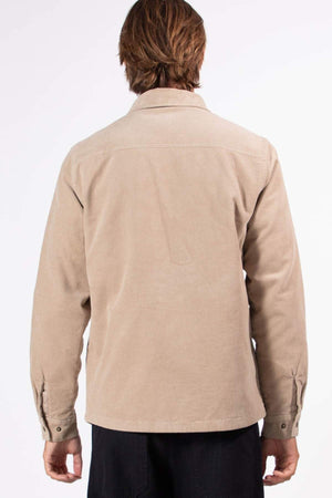 A person with medium-length brown hair, seen from behind, wears the Mr Simple Quilted Cord Jacket in light beige with snap closure and black pants against a plain white background.