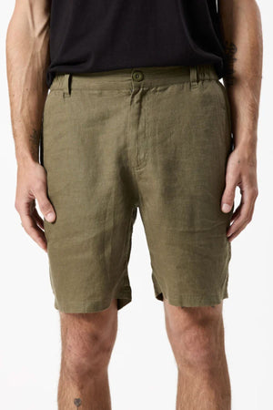 A person stands against a plain white background wearing Mr Simple Tanner 3.0 Linen Shorts in breathable olive green with an elastic waistband and a black t-shirt. The image is waist to knee cropped, arms relaxed at their sides.