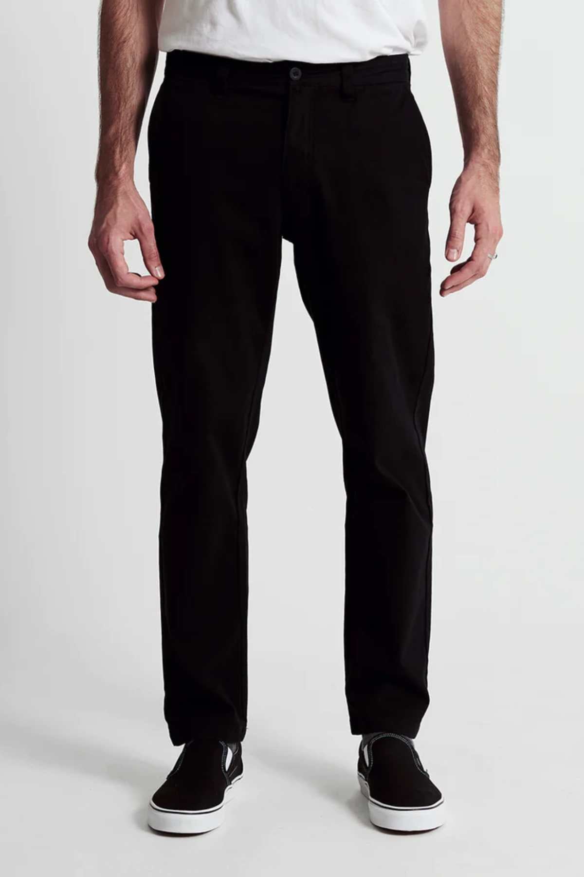 A person wears Mr Simple Wilson Standard Chino in black, a white shirt, and black slip-on shoes, standing facing forward against a plain white background. The image is cropped from the shoulders down.