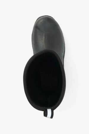 Top view of a single Muck Boot Muckmaster Mid Boot in black featuring a black and white pull tab at the back. The boot is empty and showcases a textured, solid MS-1 molded outsole for enhanced grip. Made of waterproof material, the interior is visibly dark, providing contrast with the durable outer material.