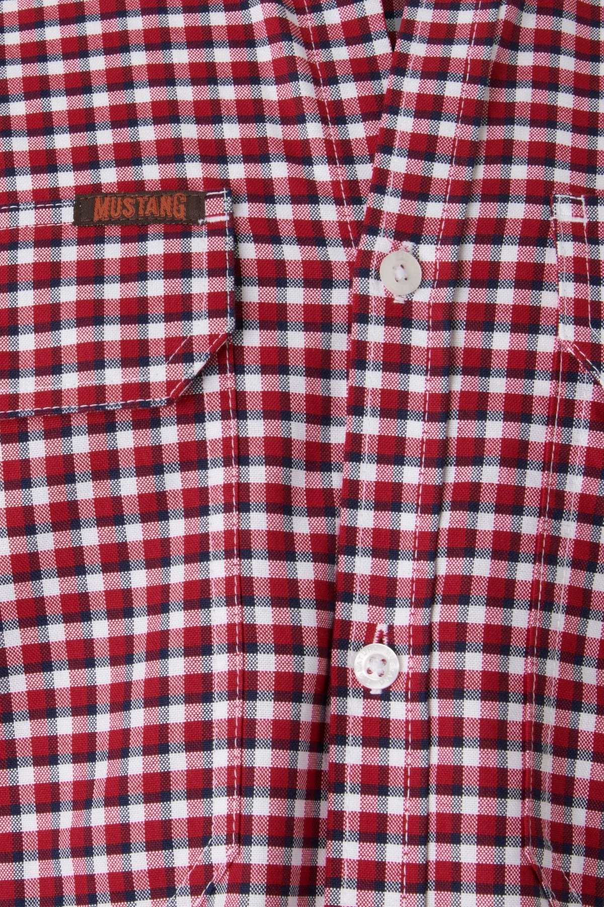 Close-up of a high-quality cotton Mustang Signature Check Shirt featuring red and white checkered patterns. Two white buttons are visible, and one of the chest pockets has a small brown tag with "Mustang Signature" embroidered on it.