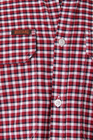 Close-up of a high-quality cotton Mustang Signature Check Shirt featuring red and white checkered patterns. Two white buttons are visible, and one of the chest pockets has a small brown tag with "Mustang Signature" embroidered on it.