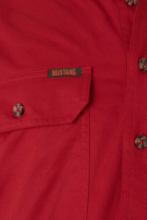 A detailed view of the Mustang Signature Closed Front Workshirt in red, featuring a buttoned pocket with a small "Mustang" label. Made from durable cotton, this men's shirt is complete with brown buttons, embodying tough workwear style.
