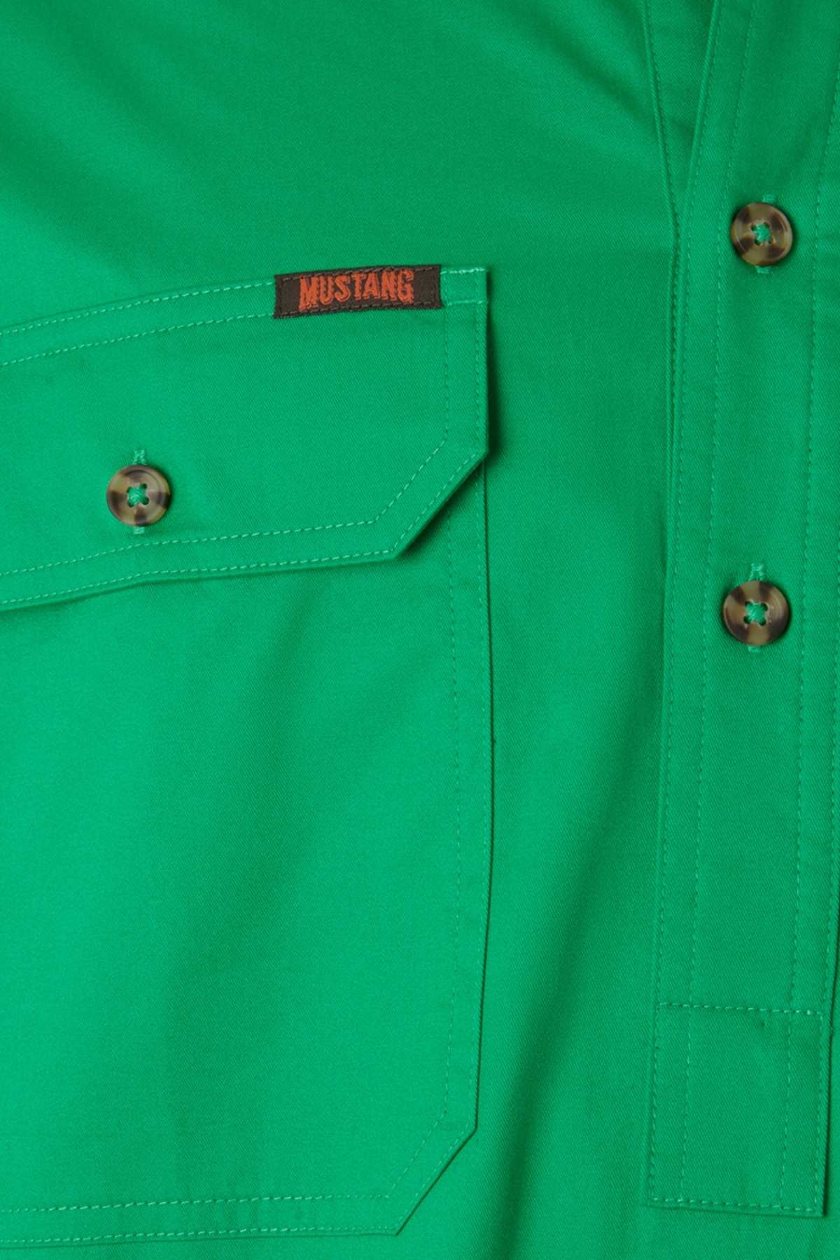 Close-up of the Mustang Signature Closed Front Workshirt in bright green. Made from soft cotton, it features a buttoned chest pocket with a red "MUSTANG" tag and three brown marbled buttons near the pocket.