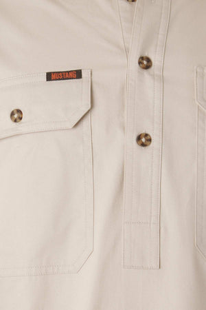 Close-up image of the Mustang Signature Closed Front Workshirt in beige, featuring a pocket with a button flap on the left chest. The pocket has a black and red "MUSTANG" label above it. This durable cotton workshirt includes a button placket with four brown buttons.