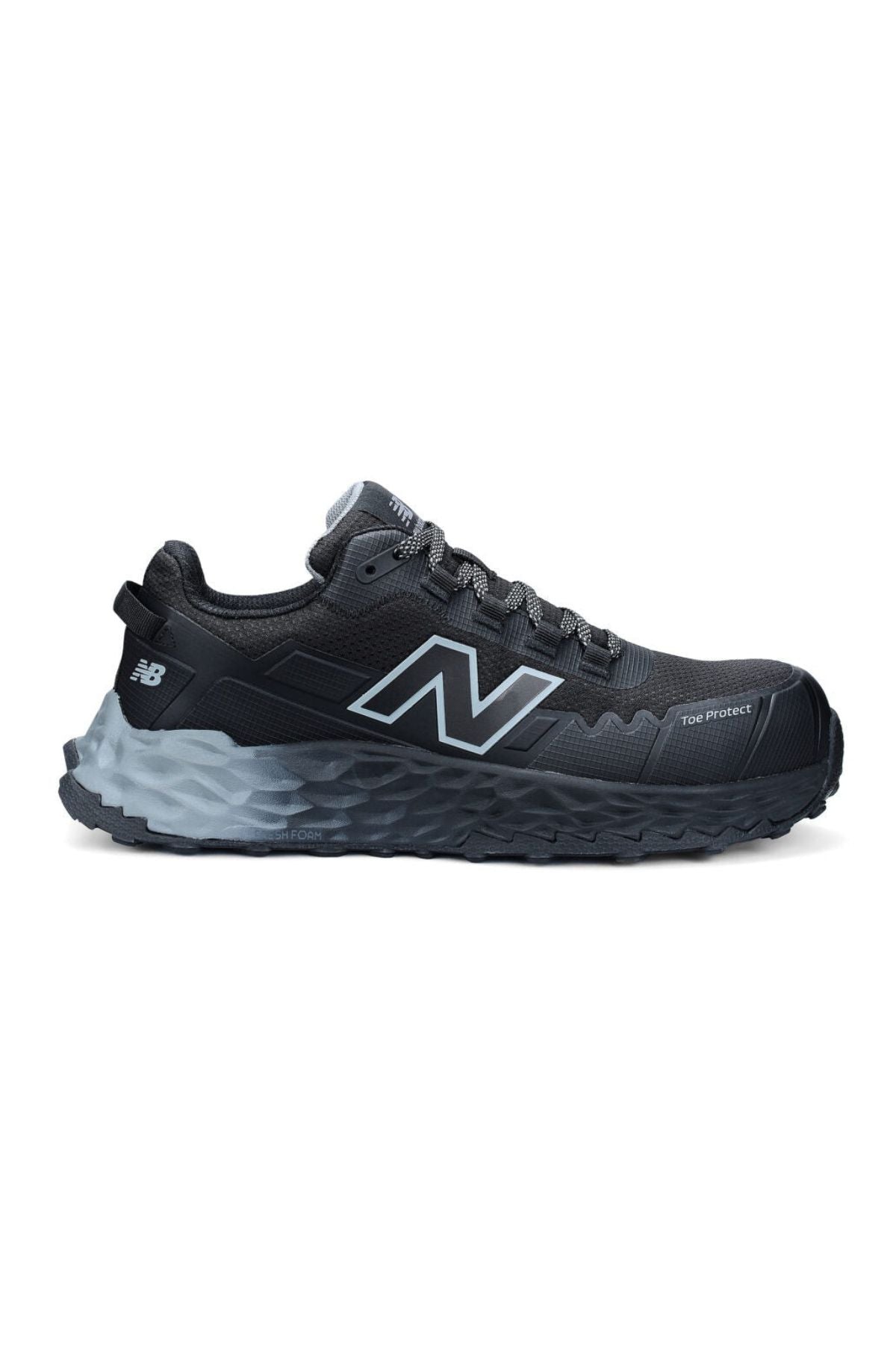 The New Balance Cremorne Safety Shoe is black and dark gray with a thick, textured slip-resistant sole, a large "N" logo on the side, and a "Toe Protect" label near the front.