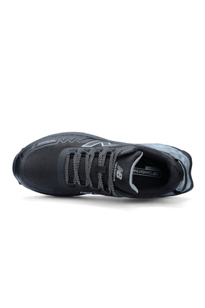The New Balance Cremorne Safety Shoe is black with a mesh upper, gray patterned laces, and branding on the tongue and side. The insole reads “NB Comfort Insert.” It features a slip-resistant sole for added protection.