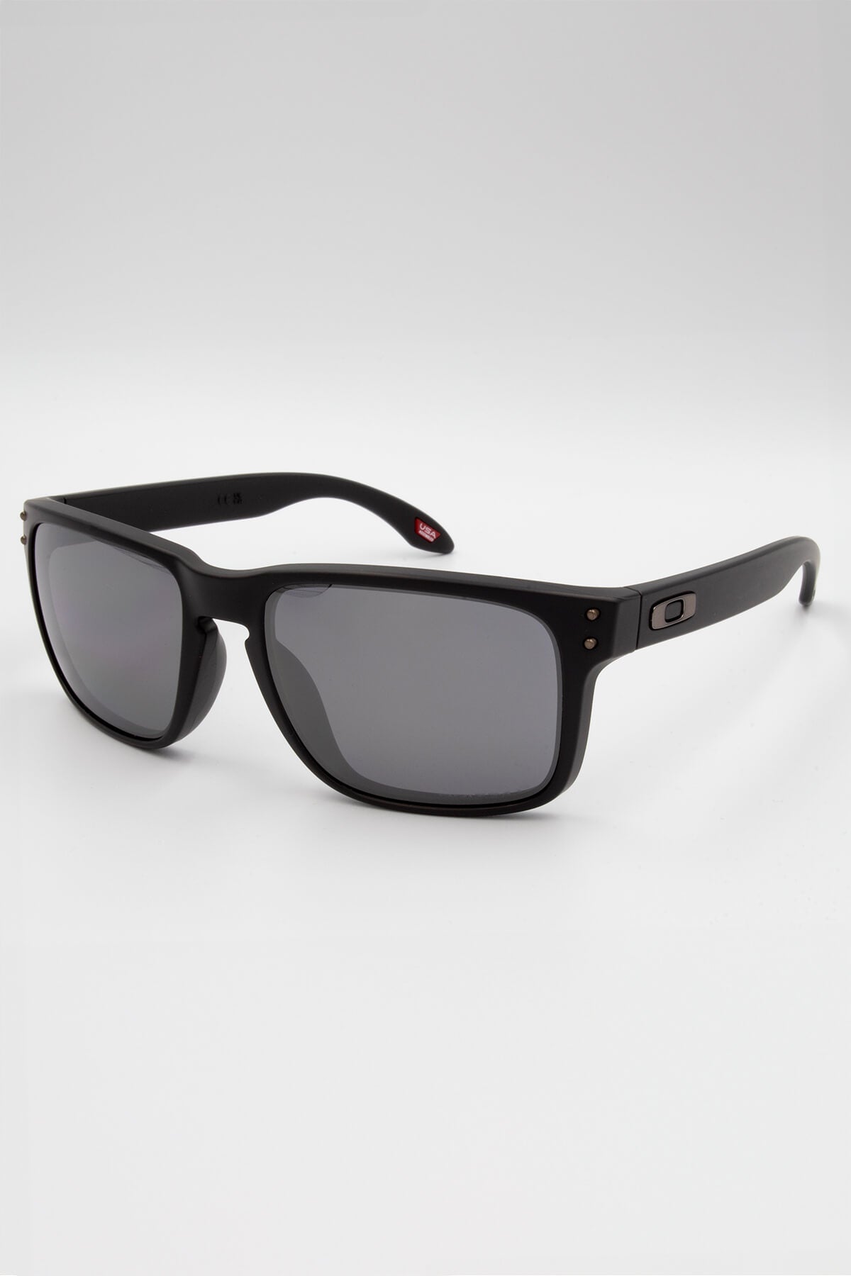 These Oakley Holbrook sunglasses have matte frames, dark black polarized lenses with Prizm technology, and a subtle logo on the side. They rest stylishly against a pristine white background.