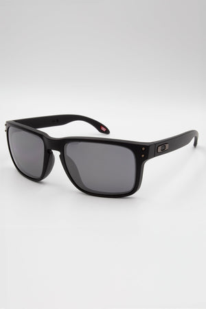 These Oakley Holbrook sunglasses have matte frames, dark black polarized lenses with Prizm technology, and a subtle logo on the side. They rest stylishly against a pristine white background.