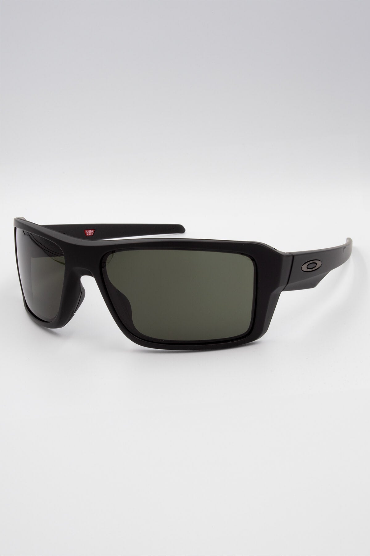 The Oakley Double Edge sunglasses feature a black rectangular frame with dark polarized lenses, a thick stress-resistant build, and the signature Oakley “O” logo on the temple, all set against a plain white background.