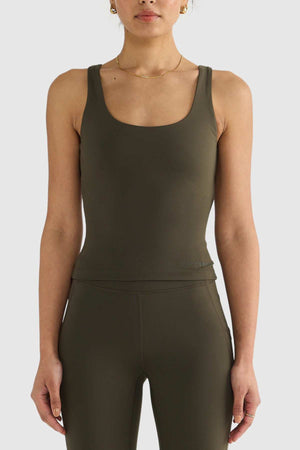 A person is wearing an ORTC Eva Twist Back Reversible Top with matching leggings in olive green, highlighting the ultra-soft double-brushed fabric. The versatile dual-wear design stands out against a plain white background.