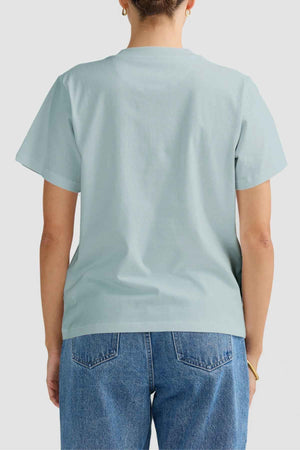 The ORTC Everyday T-Shirt in light blue provides a combination of style and comfort, seamlessly pairing with traditional blue jeans. Its minimalist design is highlighted against a simple light gray backdrop, creating an everlasting aesthetic.