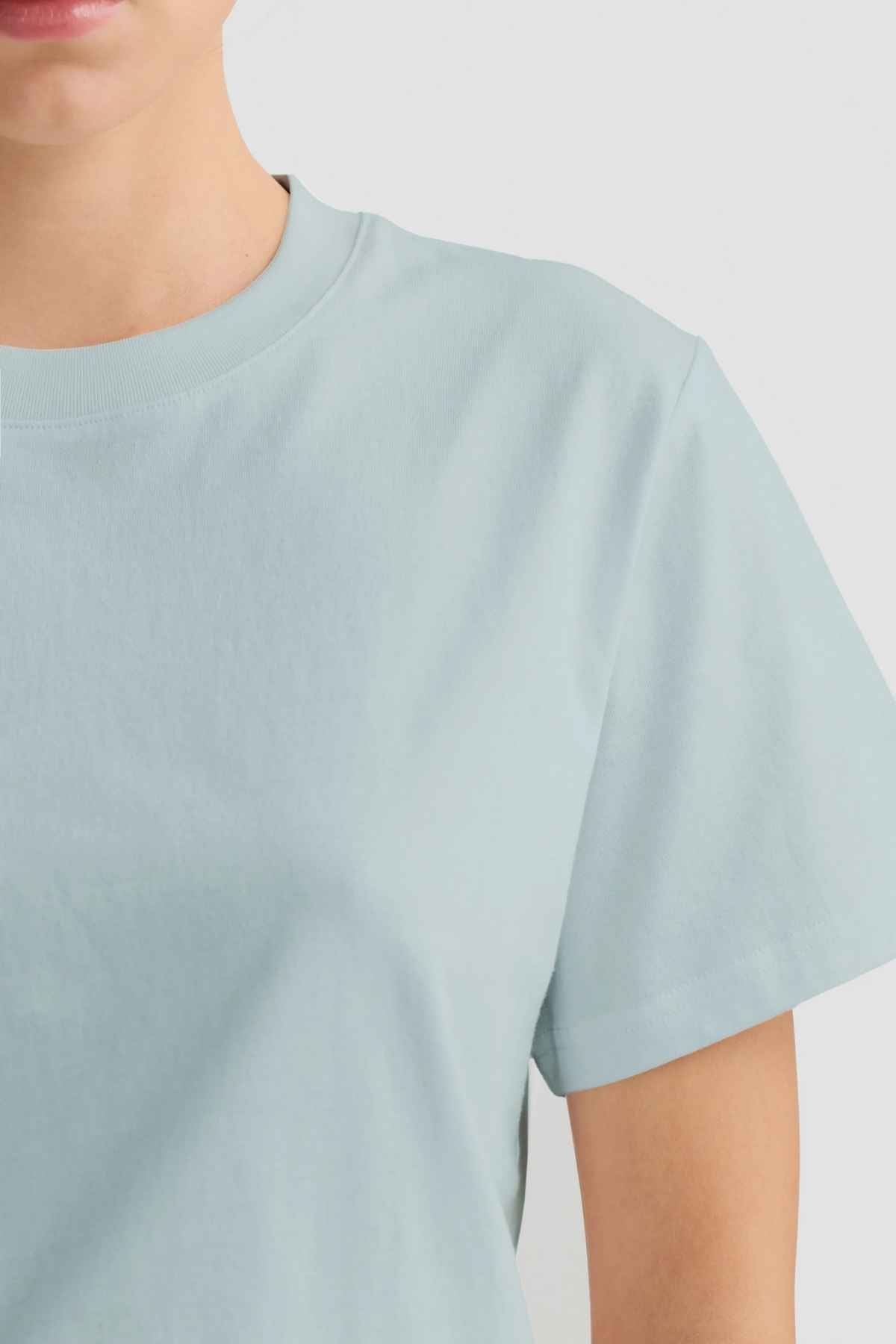 A person dressed in a light blue ORTC Everyday T-Shirt is partially visible, with an emphasis on the upper torso, showcasing the T-shirt's comfort and style against a simple backdrop.