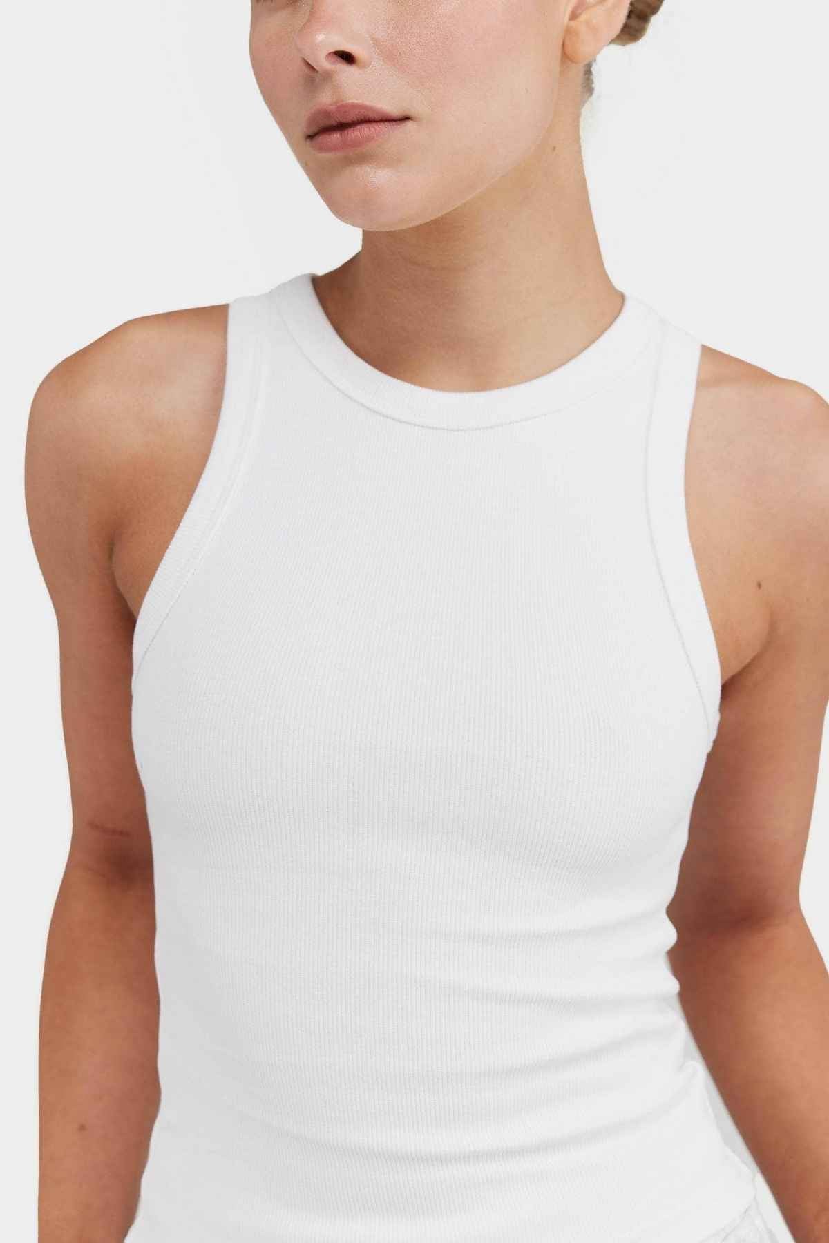An individual wearing the ORTC Mimi Rib Tank stands against a plain background. The image focuses on the upper torso and neck, emphasizing the ribbed knit fabric's texture and fit, making it an ideal layering piece for any ensemble.