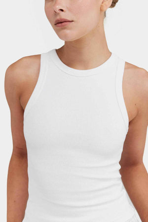 An individual wearing the ORTC Mimi Rib Tank stands against a plain background. The image focuses on the upper torso and neck, emphasizing the ribbed knit fabric's texture and fit, making it an ideal layering piece for any ensemble.