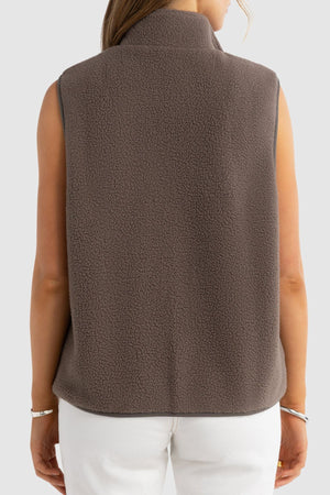 A person is shown from the back wearing the ORTC Sully Sherpa Fleece Vest in brown with white pants against a plain light gray background—ideal for effortless layering.