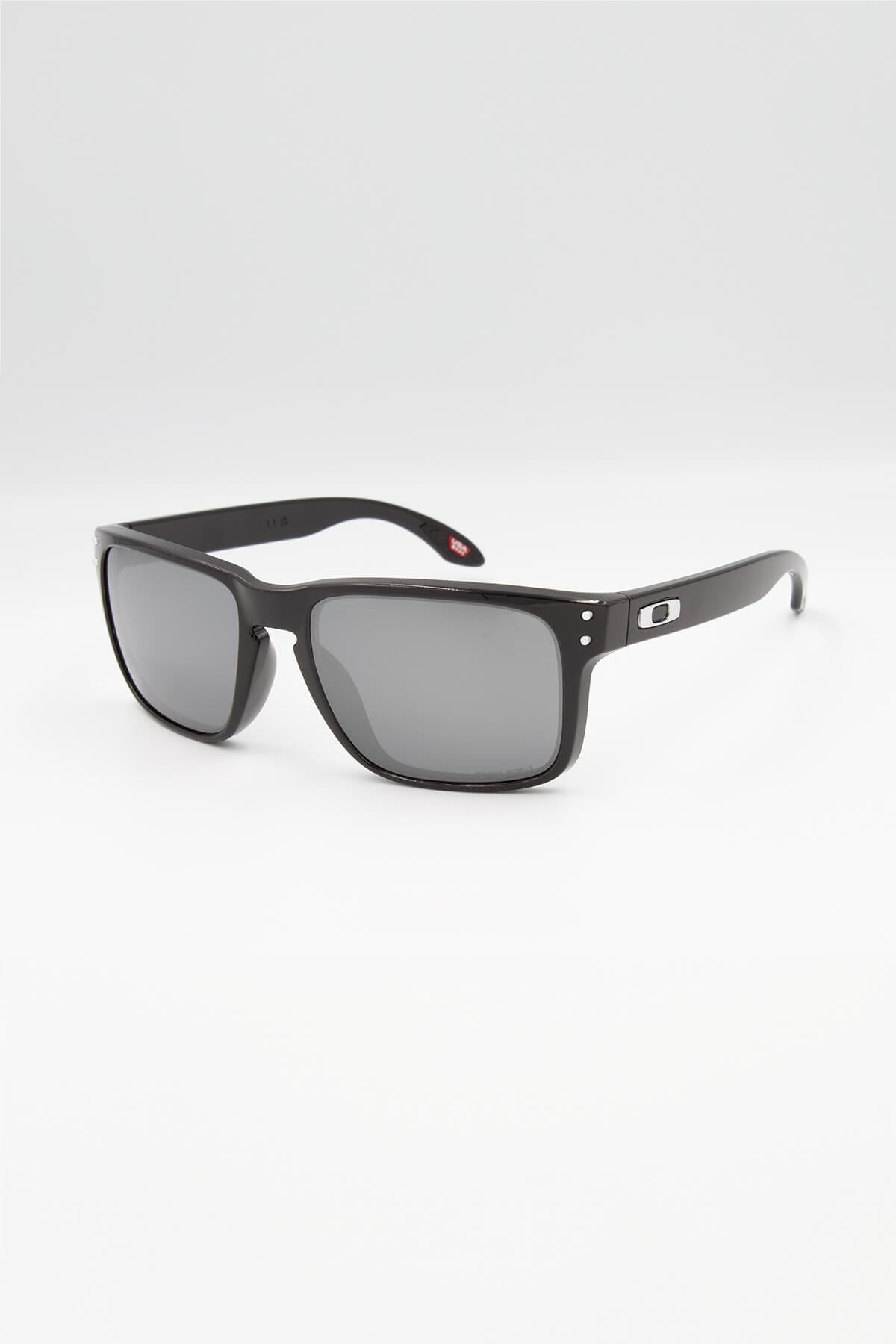 The Oakley Holbrook sunglasses, with dark lenses and a small logo on thin arms, exemplify timeless style. Set at an angle on a plain light background, they highlight sleek, modern design.