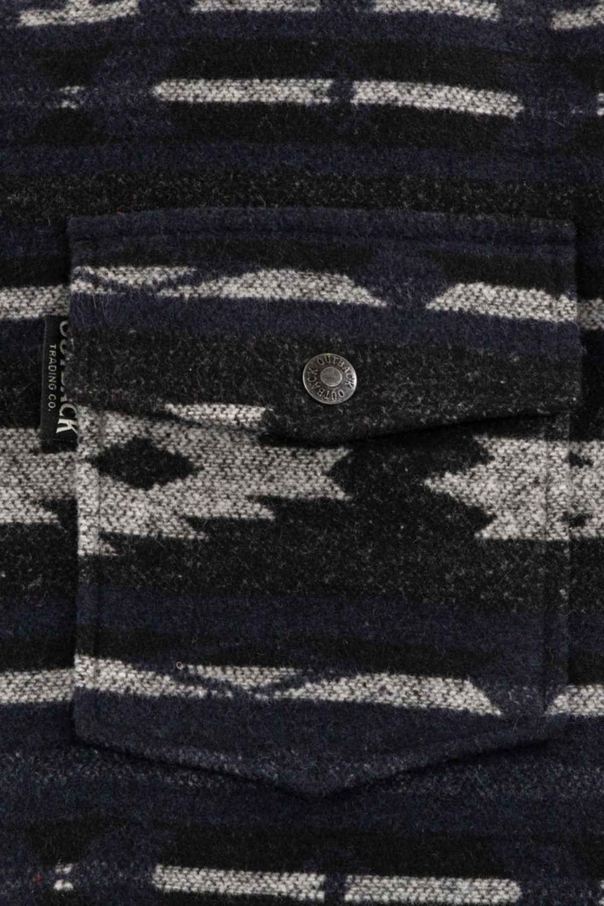 Close-up of the Outback Marc Jacket showing its brushed shell with an abstract, geometric black and gray pattern, a 2-way zipper, front flap pocket with a metal button, and a small fabric tag on the left side.