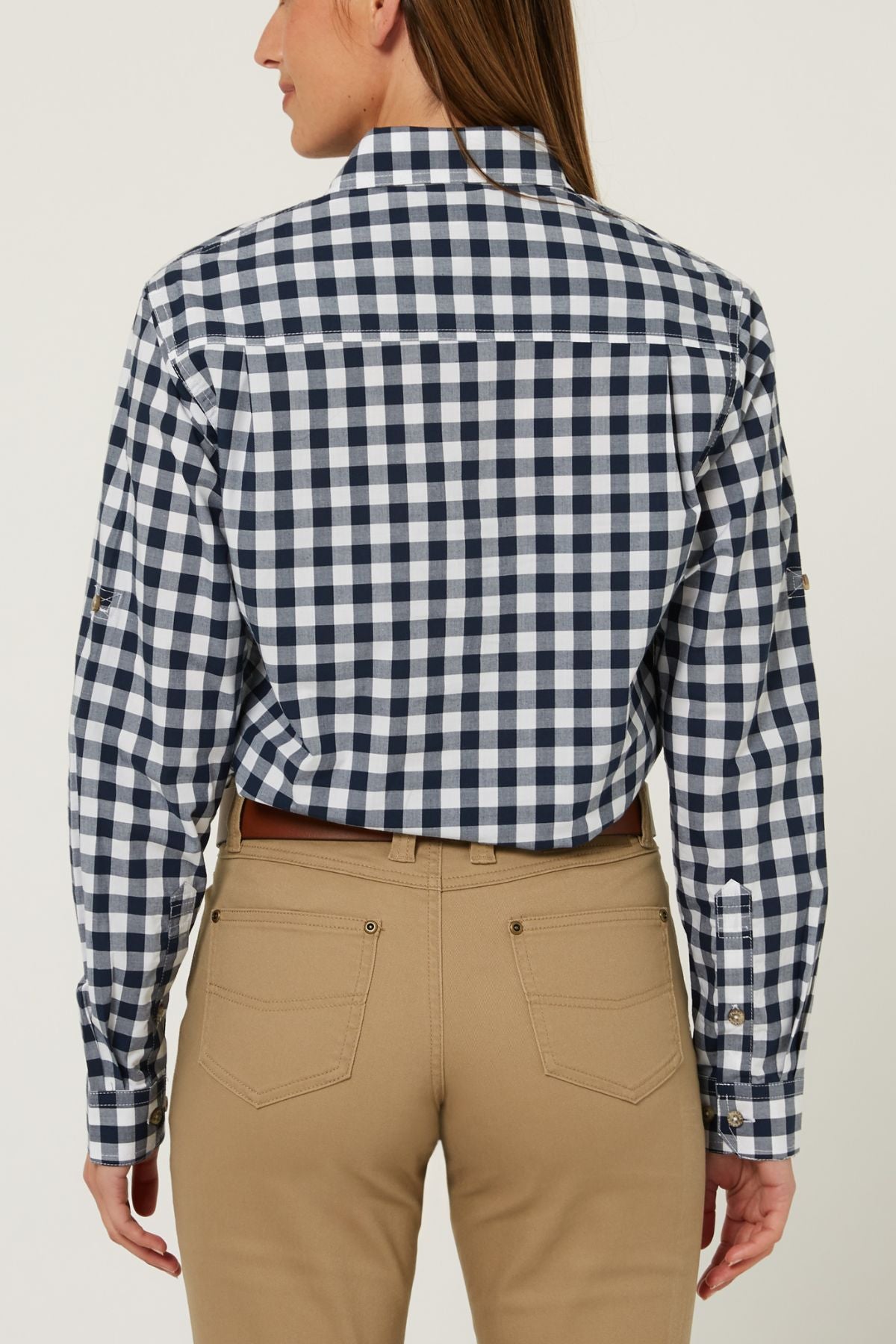 A person wearing the Pilbara Ladies Check Closed Front Long Sleeve Shirt in navy and white, paired with tan pants, shown from the back against a plain background.