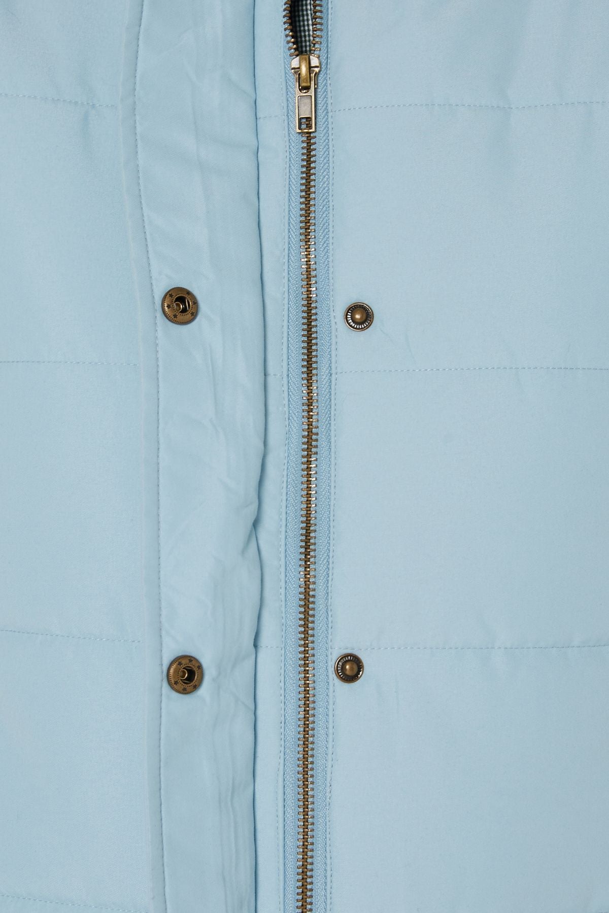 Close-up of the Pilbara Ladies Vest in light blue, showcasing quilted texture, polyfill padding, a zipper closure, and metallic snap buttons along the front placket. The detailed stitching and fabric texture are clearly visible.