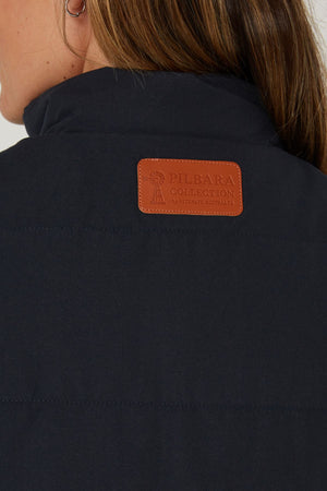 Close-up of a person's back wearing the Pilbara Ladies Vest, featuring polyfill padding and a brown leather collar patch that reads "PILBARA COLLECTION by Ritemate Australia." Part of the person's hair is visible.