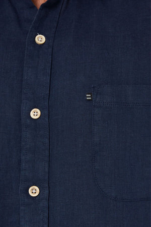 Close-up of the Pilbara Linen Shirt, a dark blue long-sleeve shirt with a left chest pocket and light brown buttons.