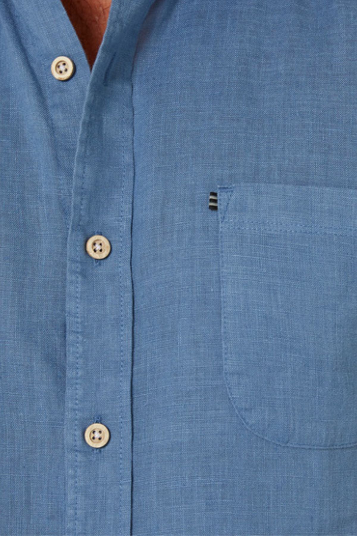 Close-up of the Pilbara Linen Short Sleeve Shirt in light blue, showcasing beige buttons and a left front pocket.