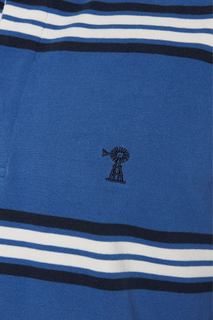The Pilbara Rugby Jersey features blue fabric with horizontal white and navy stripes plus a central small black windmill embroidery, echoing the style of a classic rugby jersey.