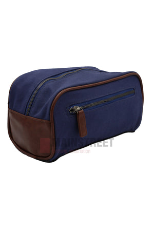 The Pilbara Toiletry Bag features navy blue premium canvas with brown leather accents and a top zipper, ideal for organizing travel essentials. Shown on a white background.