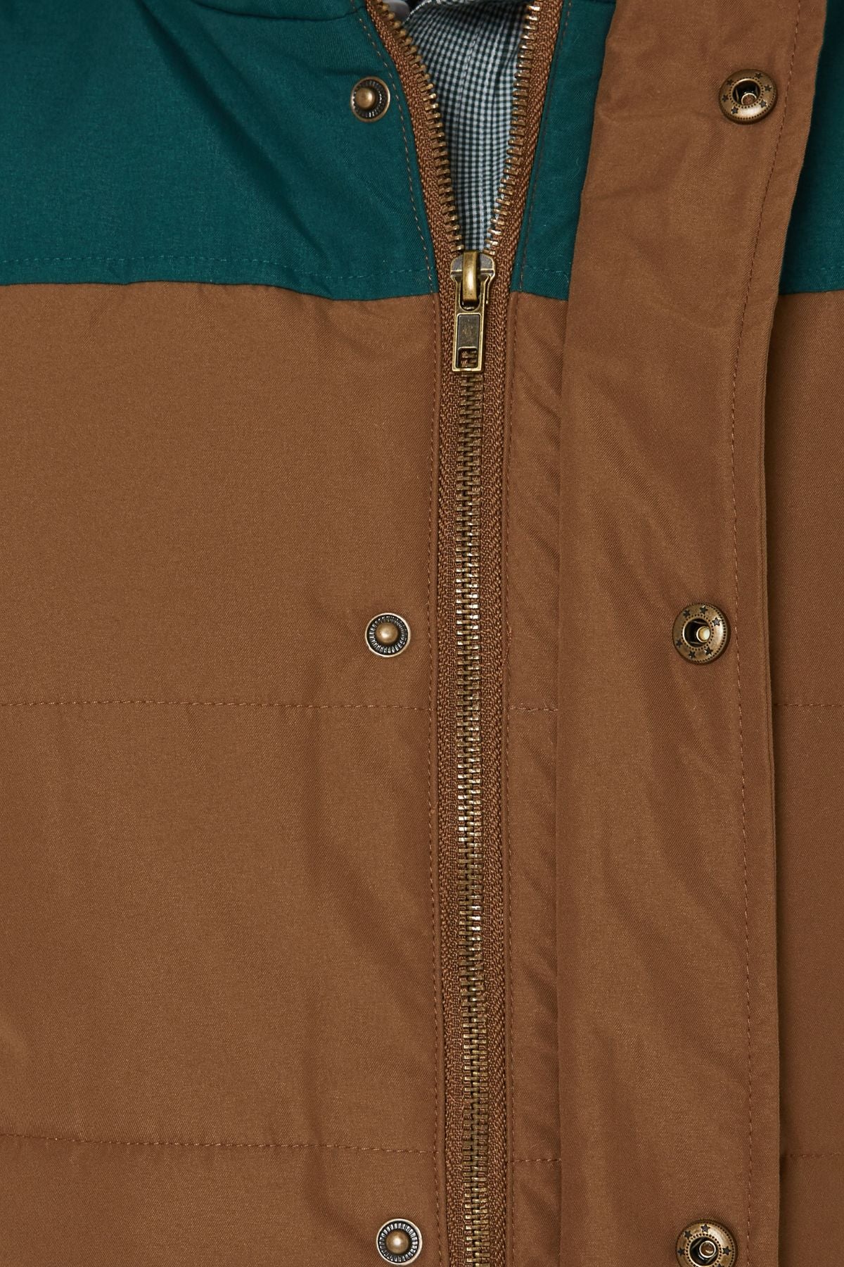 Close-up of the Pilbara Two Tone Vest in brown and teal, featuring a partially open zipper, snapped buttons, quilted fabric, and a peek at the patterned inner lining near the collar.