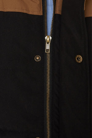 Close-up of the Pilbara Two Tone Vest, featuring a classic fit, metal zipper, brown and black color block design, blue and white checkered shirt fabric behind the zipper, and two metallic snap buttons on the black section.