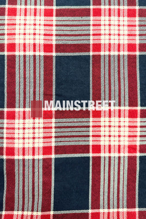 The Pilgrim Closed Front Flannelette Shirt features a red, white, and navy blue large plaid pattern with intersecting lines. Made from 100% cotton, it has long sleeves and "MAINSTREET" printed boldly in white across the center.
