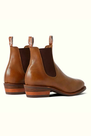 The RM Williams Comfort Lady Yearling Rubber Sole Boots are women's brown leather Chelsea boots with a slight heel, elastic side panels, and back pull tabs. Made in Australia, they feature a comfort insole for all-day wearability and exude elegance and functionality when viewed from the back and angled side.