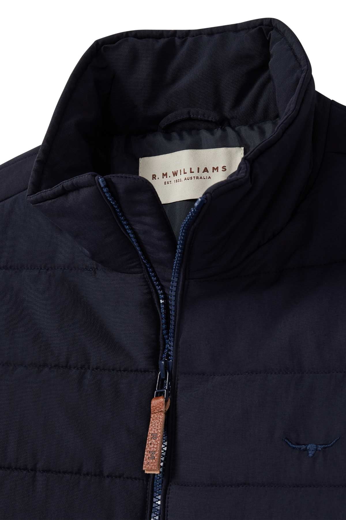 Close-up of the RM Williams Patterson Creek Jacket in navy, showcasing its quilted design, stand-up collar, brown leather zipper pull, internal R.M. Williams label, and small embroidered chest logo.