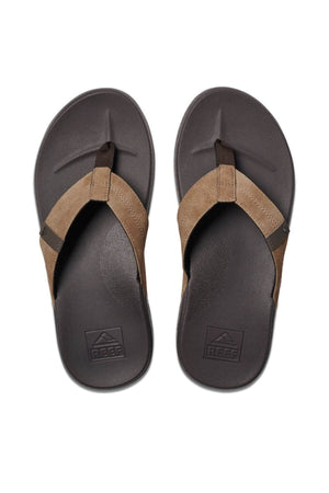 Brown and black flip-flops with a leather-like strap and textured sole for added comfort. The REEF Cushion Phantom name is embossed on the footbed, ensuring durability with every step.