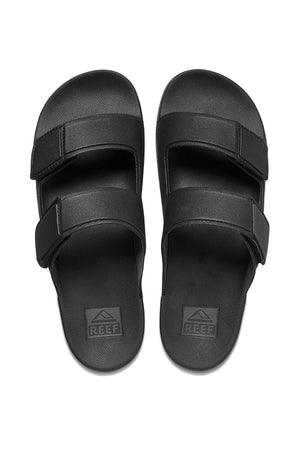 A pair of black REEF Cushion Tradewind sandals with two adjustable Velcro straps per sandal and the Reef logo on the cushion footbed, shown on a white background.