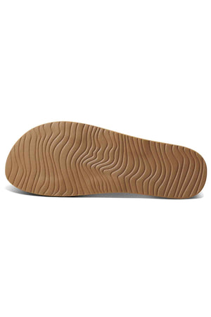 The REEF Cushion Vista sandal showcases a brown sole with a wavy, textured design for grip and arch support against a white backdrop.