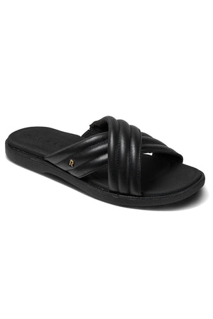 The REEF Lofty Lux X is a black slip-on sandal with padded crisscross straps, a flat sole for comfort, and a subtle metallic accent on the side.