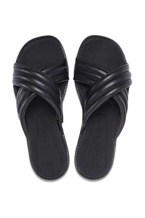 A pair of REEF Lofty Lux X black slip-on sandals with crisscross padded straps and open toes, shown on a white background—ideal for anyone seeking premium comfort and sustainable style.