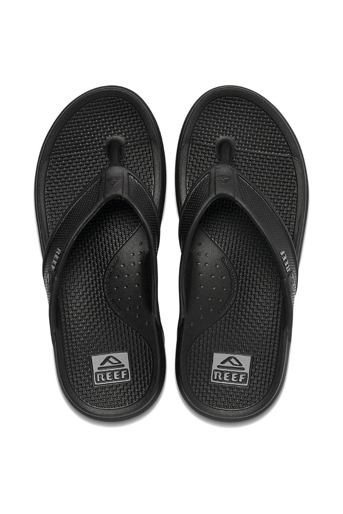 A pair of REEF Oasis sandals in black, featuring textured footbeds and the Reef logo on both the heel area and straps, are made with renewable sugarcane EVA for reliable arch support. These flip-flops are placed side by side, facing upward on a white background.