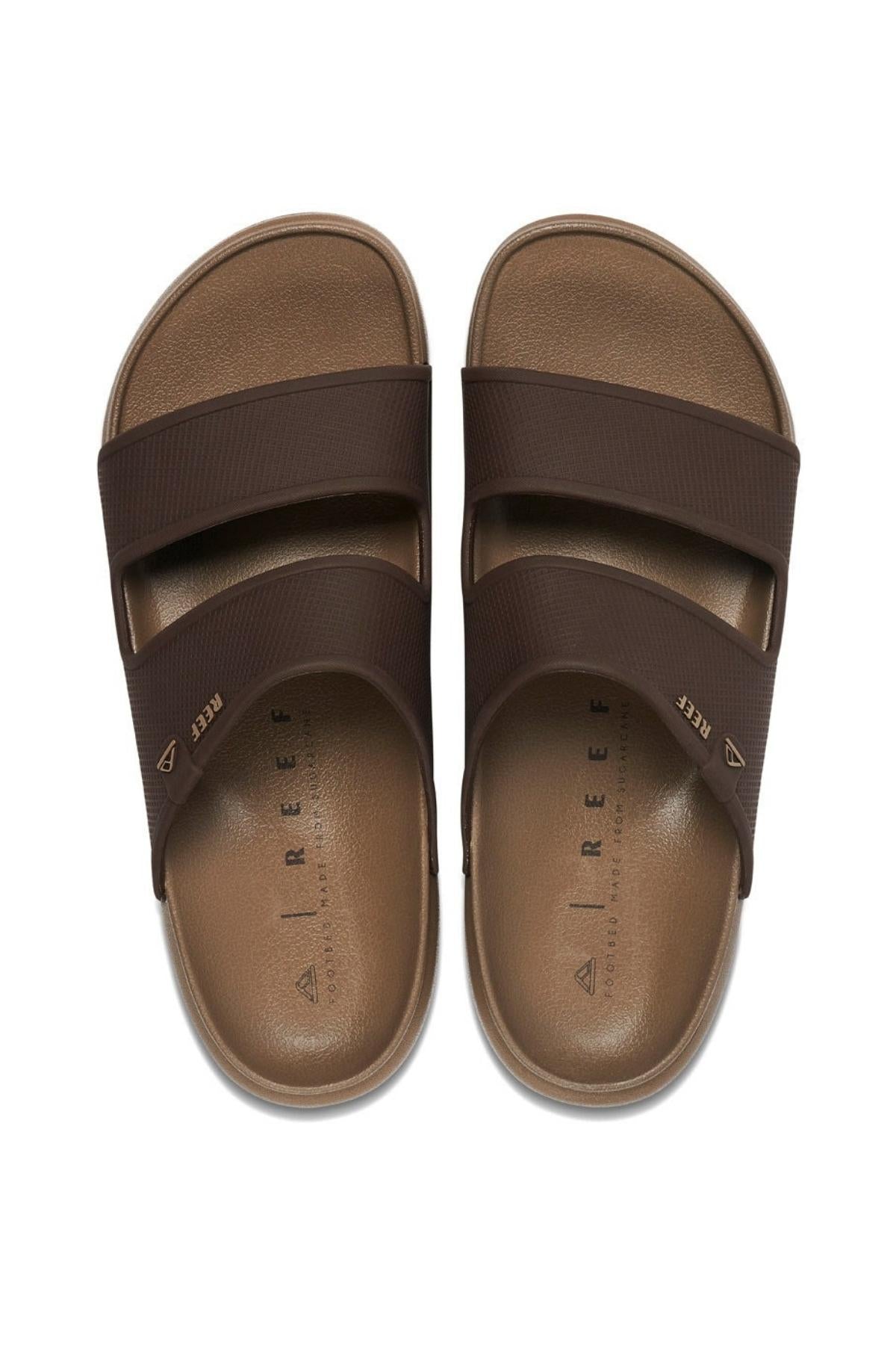 A pair of REEF Oasis Double Up slide sandals, brown with two wide straps per foot, shown from above on a white background. The tan footbeds offer arch support and are branded "REEF" inside each sandal.