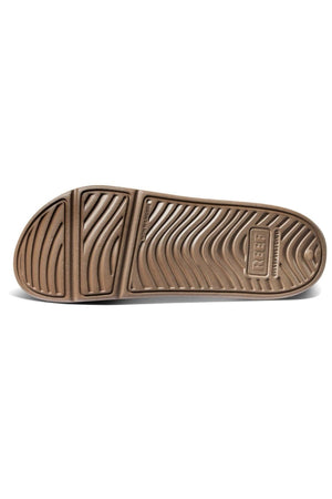The image shows the sole of the REEF Oasis Double Up sandal, featuring a wavy textured pattern, the "REEF" logo near the heel, built-in arch support, and a renewable sugarcane EVA footbed.