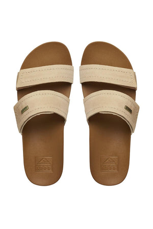 The REEF Velcro Vista SE are tan slide sandals with premium leather straps, a brown footbed with cushion bounce midsole, "Reef" embossed on the footbed, and a small label on the straps. They are viewed from above.