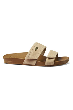 The REEF Velcro Vista SE is a tan sandal with two wide leather straps and a contoured sole. Its minimalist design features soft suede-like material, a cushion bounce midsole for comfort, and a slightly textured sole for grip.