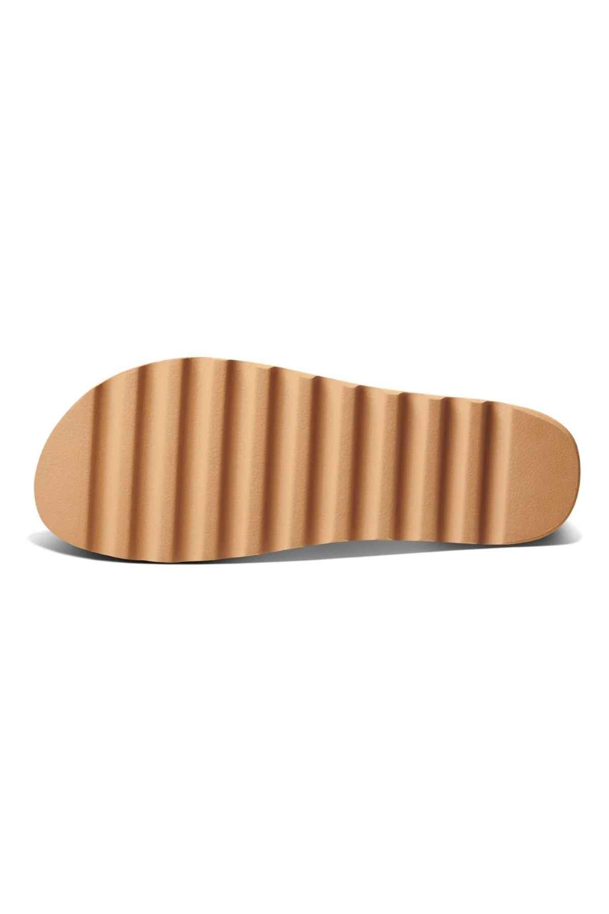 A tan REEF Vista Hi Buckle sandal sole, shown from below against a white background, features a wavy, ridged tread and is crafted with premium vegan leather.