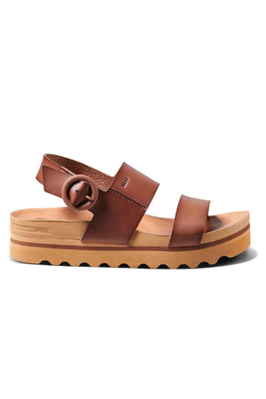 The REEF Vista Hi Buckle sandal showcases straps made from vegan leather and a chunky sole. This platform sandal is designed with a prominent buckle and features a slightly raised platform along with a textured rubber bottom to enhance grip.