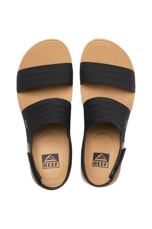 Top view of REEF Water Vista sandals, featuring textured tan soles, two wide black straps providing excellent arch support, and visible brand logos on the insole and strap sides.